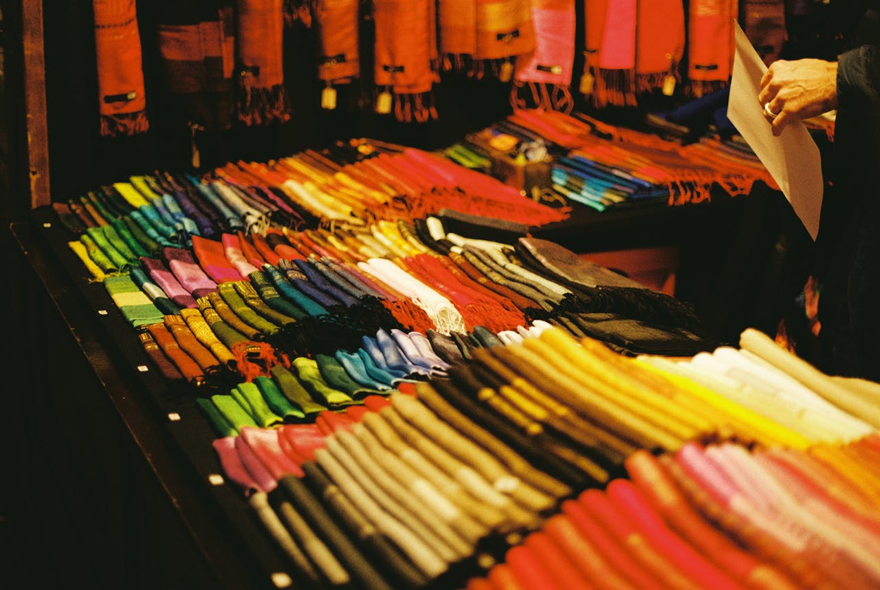 portfolio-06 A vibrant display of scarves at a Berlin Christmas market stall, showcasing a variety of colors.